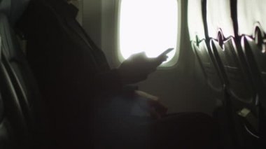 Genç adam bir pencere yanında bir smartphone içinde bir uçak kullanıyor.