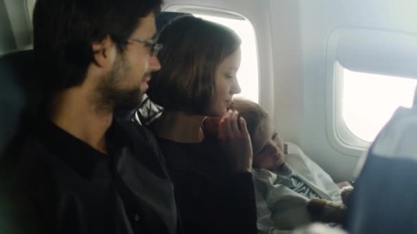 Romantischer Moment mit einer Familie mit Kind an Bord eines Flugzeugs neben einem Fenster. — Stockvideo