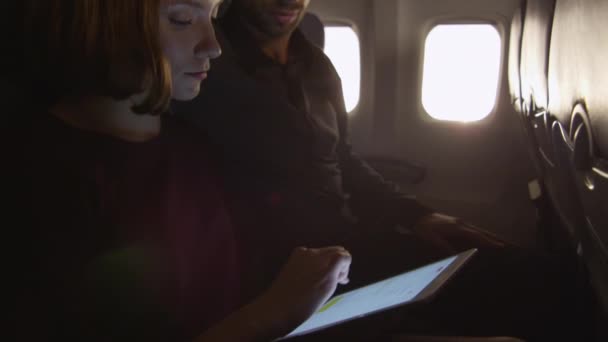 Пара сидит вместе на самолете и использует планшет . — стоковое видео