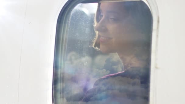 若い女性は、飛行中に飛行機の窓と笑顔を通して見える. — ストック動画