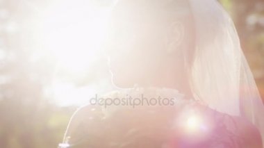 Gelinlik gelin bir güneşli parkta çiçekli portresi.