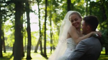 Gelin ve damat birbirine güneşli parkta sarılmak.