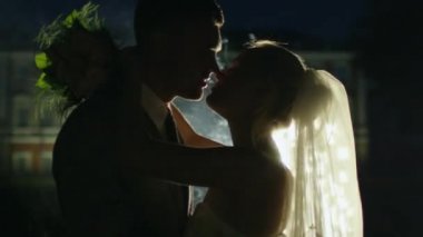 Mutlu genç newlyweds yanındaki bir parkta havai fişek akşam öpüşme.