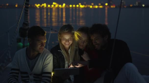 Grupp människor använder surfplatta på en yacht i havet på kvällen. — Stockvideo