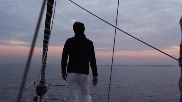 L'homme lève les mains d'une manière relaxante sur un voilier dans la mer . — Video