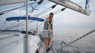 Genç adam yatta yürür ve denizin telefonda konuşuyor.