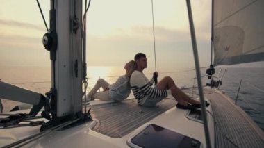 Genç çift rahatlatıcı günbatımı denizde bir yatta.