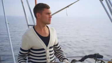 Genç adam denizde bir yelkenli tekneyi kullanıyor.