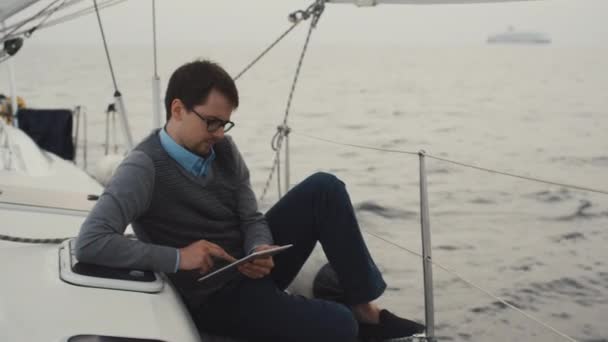 Man gebruikt Tablet PC op een jacht in de zee. — Stockvideo