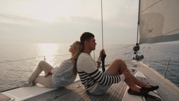 Pareja joven relajándose en un yate en el mar al atardecer . — Vídeos de Stock