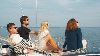 Bir grup insan güneş gözlüklü bir yelkenli üzerinde rahatlatıcı.