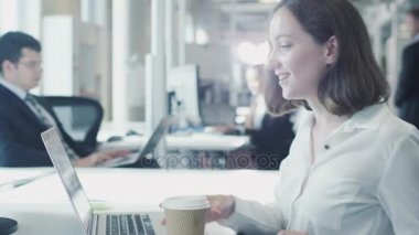 Kadın memur Laptop ve içme kahve üzerinde çalışıyor
