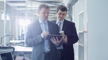 İki iş adamları aracılığıyla Office yürüyüş vardır. Ofis işçi Holding Tablet Pc.