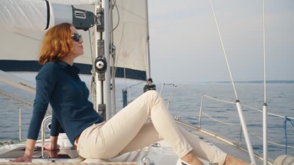 Mooie vrouw in zonnebril is ontspannend op een jacht in de zee. — Stockvideo
