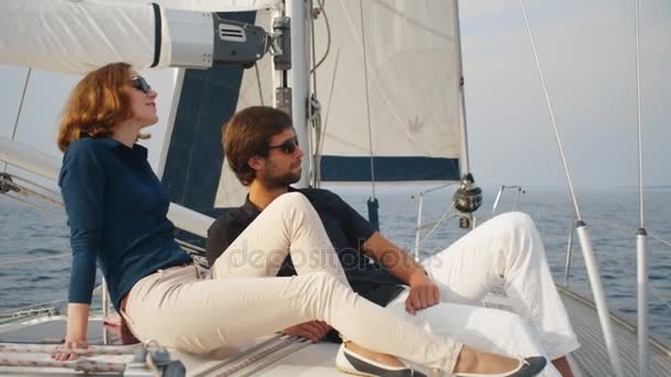 Пара в сонцезахисних окулярах розслабляється на вітрильному човні в морі . — стокове відео