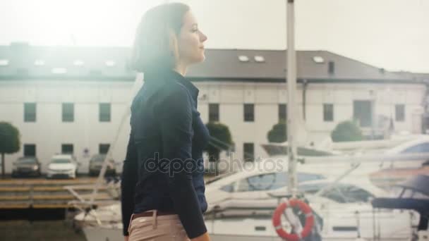 Belle femme marchant autour du port de mer avec des yachts par une journée ensoleillée . — Video