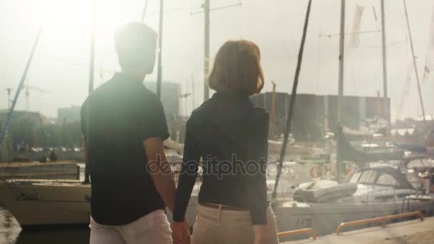 Όμορφο ζευγάρι περπάτημα γύρω από το λιμάνι με τα σκάφη σε μια ηλιόλουστη ημέρα. — Αρχείο Βίντεο