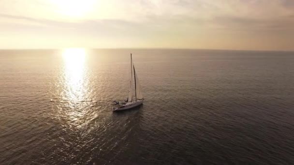 Lanzamiento de un dron aéreo de un velero en el mar al atardecer . — Vídeo de stock