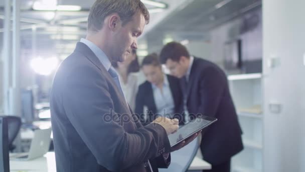 Uomo d'affari che lavora su tablet in ufficio affollato — Video Stock