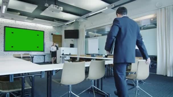 Büroangestellte kommen in den Konferenzraum. an der Wand ist ein Display mit grünem Bildschirm. — Stockvideo