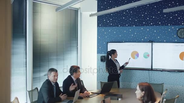 Une femme fait une présentation pour un groupe d'hommes d'affaires dans une salle de conférence . — Video