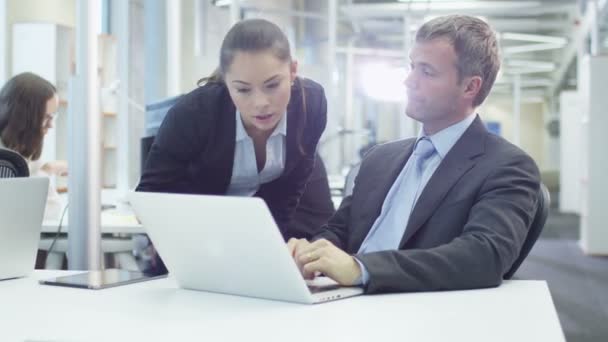 Два офисных работника беседуют рядом с компьютером — стоковое видео