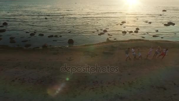 Letecká dron shot mládeže tahání lana na pláži při západu slunce. — Stock video