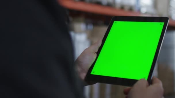 Εργαζόμενος περπατώντας στα Logistics αποθήκη κρατώντας Tablet με πράσινη οθόνη στα χέρια — Αρχείο Βίντεο
