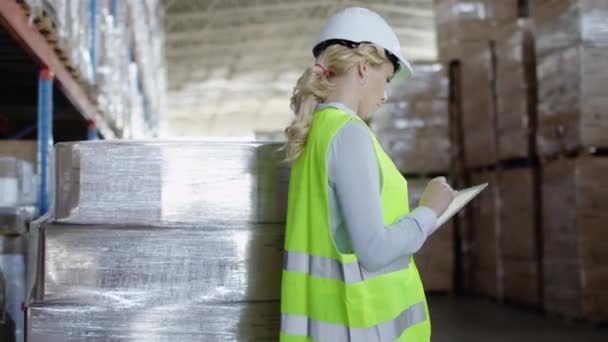 Mulher trabalhadora em chapéu duro trabalhando em tablet no armazém logístico — Vídeo de Stock