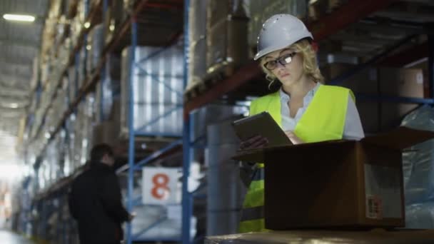 Female Manager of Logistics Warehouse is Working on Tablet PC. Wears a White Hard Hat. — Stock Video
