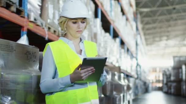 Travailleur féminin de l'entrepôt logistique travaille sur Tablet PC. Porte un gilet de sécurité .