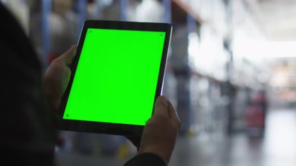 Trzymając komputer typu Tablet z zielonym ekranem w magazyn logistyczny. Makiety. — Wideo stockowe