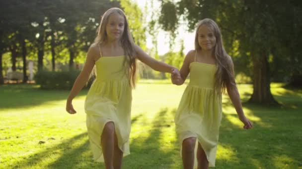 Dvě dívky, které jsou spuštěny v slunečním světle v parku — Stock video
