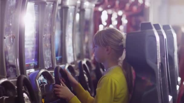 Девочка играет в видеоигру Racing Arcade в развлекательном центре — стоковое видео