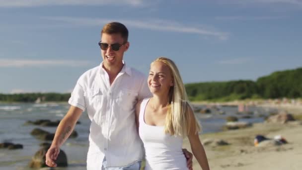 Casal feliz está andando na praia no dia ensolarado. Movimento lento 60 FPS . — Vídeo de Stock