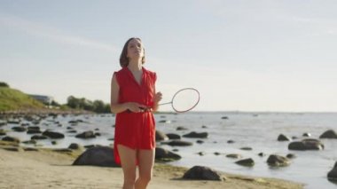 Genç kız sahilde badminton oynuyor