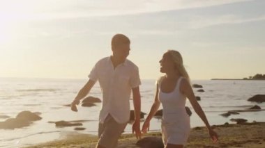 Çift sahilde eğleniyor. Adam taşıyan kız kollarını ve Whirling.