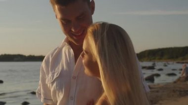 Çift birbirlerine kucaklayan ve birlikte sahilde gün batımında izlerken