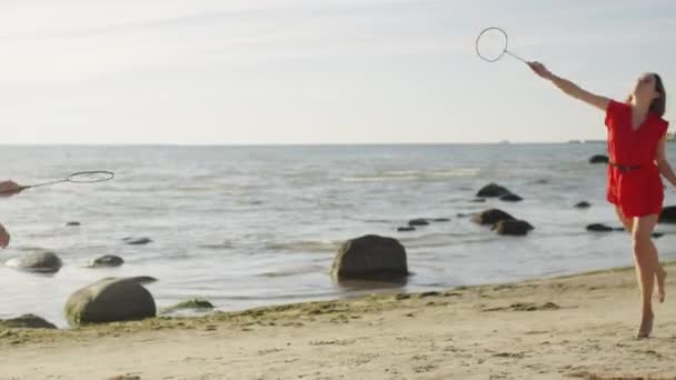 Giovane uomo e ragazza stanno giocando a Badminton sulla spiaggia — Video Stock