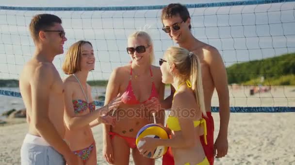 Χαμογελώντας ομάδα φίλων έχουν συνομιλία στην παραλία μετά το παιχνίδι βόλεϊ. — Αρχείο Βίντεο