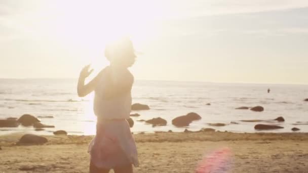 Whirling ευτυχισμένο κορίτσι τρέχει, και έχει τη διασκέδαση στην παραλία στο φως του ήλιου — Αρχείο Βίντεο