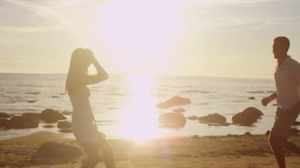 행복 한 커플 해변에서 실행 하는 재미입니다. 남자는 팔에 석양 빛에 돌면서 들고 소녀. — 비디오