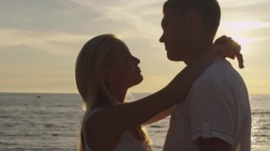 Kız ve erkek kucaklayan birbirleriyle ve öpüşme sahilde günbatımı ışığı