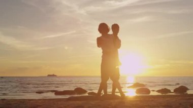 Kız ve adam sahilde birlikte eğleniyor. Elele ve gün batımı zamanında döne döne.