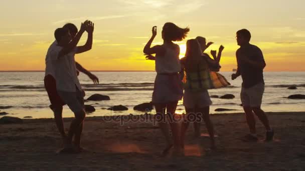 Groep van gelukkige jonge mensen zijn dansen op het strand bij zonsondergang licht. Slow Motion 60 Fps. — Stockvideo