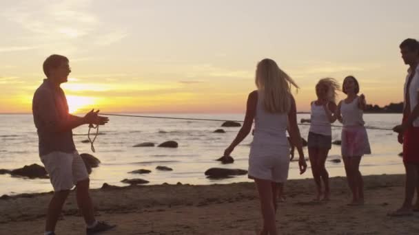 Groupe de jeunes qui s'amusent sur la plage au coucher du soleil . — Video