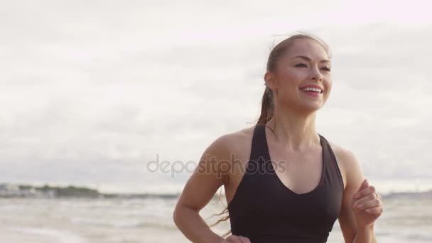 A seguito di colpo di sorridente ragazza in esecuzione in spiaggia al tramonto — Video Stock