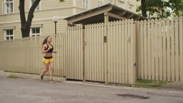 Девушка бежит в утреннее время в жилом районе — стоковое видео