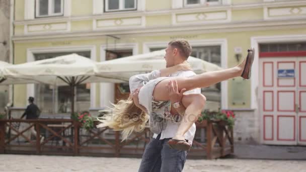 Homem está carregando namorada em braços e rodopiando — Vídeo de Stock