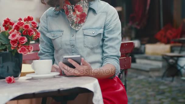 Νεαρό κορίτσι είναι χρησιμοποιώντας κινητό τηλέφωνο στην εξωτερική καφετέρια — Αρχείο Βίντεο